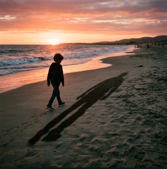a lone figure walking along a beach at sunset, their long shadow stretching behind them across the sand.”